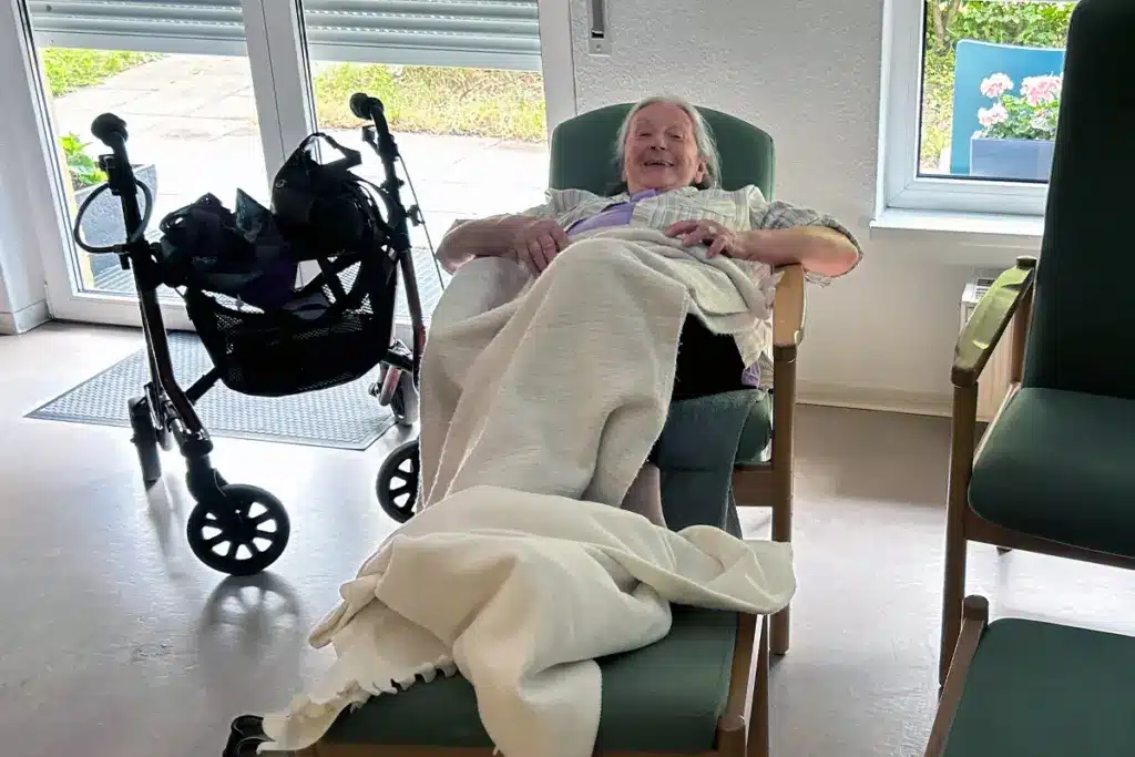 Eine Seniorin entspannt im Ruheraum der Tagespflege Palisadenstraße und genießt die Pause nach dem Mittagessen.