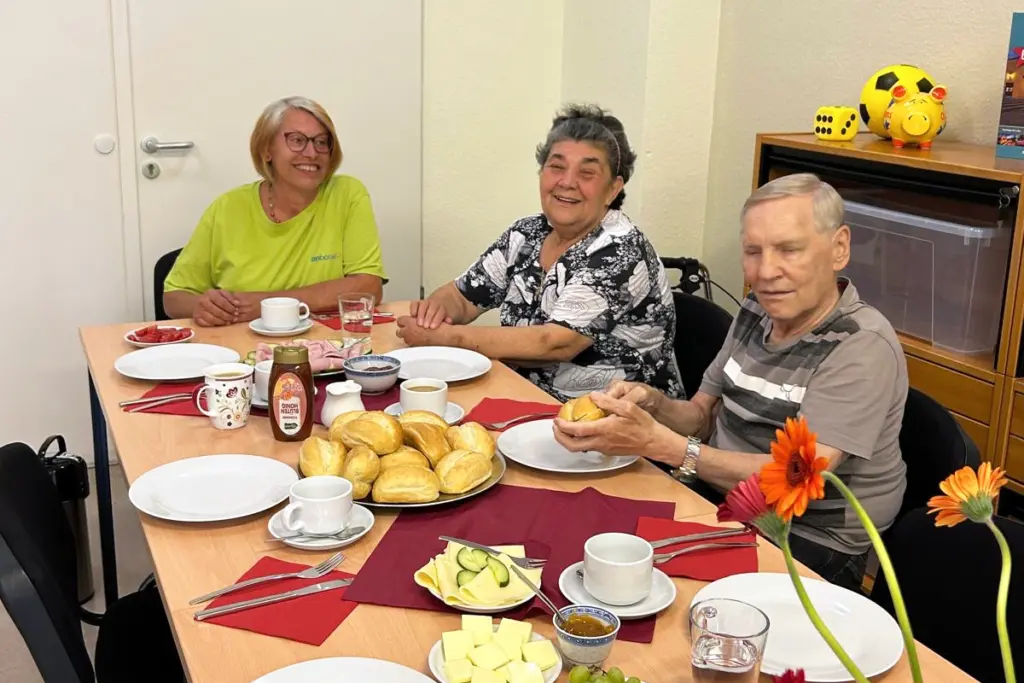 Drei Gäste und eine Mitarbeiterin sitzen zusammen am gedeckten Frühstückstisch und starten gemeinsam in den Schnuppertag.