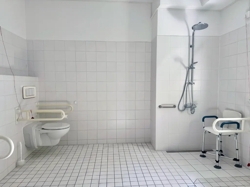 Pflegebad mit ebenerdiger Regen-Dusche, Haltegriffen und Duschstuhl in der Tagespflege Palisadenstraße Berlin