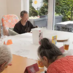 Spaß in der Tagespflege: Seniorinnen und Senioren nehmen an einem fröhlichen Schaumkusswettessen teil.